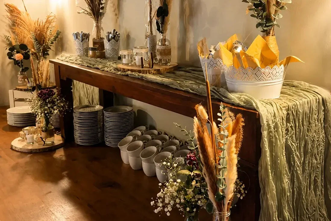 Buffettisch mit Geschirrstapeln, Servietten und Trockenblumen-Deko