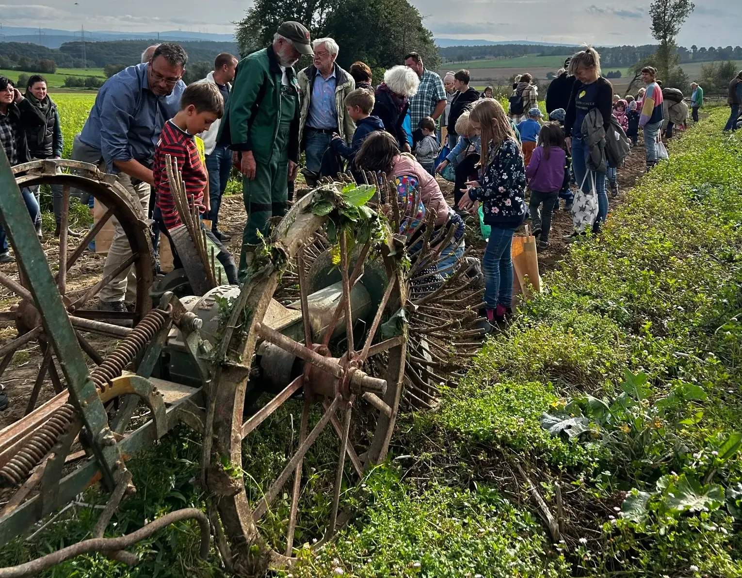 Besuchergruppe an einer historischen Erntemaschine bei einer Hofaktion am Feld