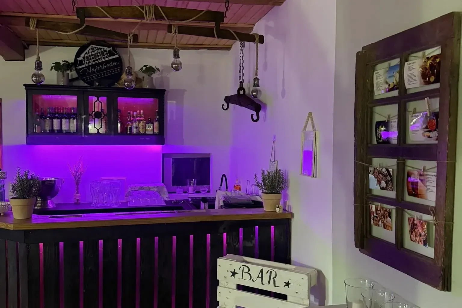Beleuchtete Bar mit Holztheke, Gläsern und Getränkekarten am Abend